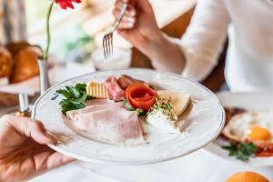 una persona che tiene un piatto di cibo su un tavolo di Hotel Blaue Gams ***S a Ettal