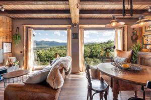 ein Wohnzimmer mit einem Tisch, Stühlen und Fenstern in der Unterkunft Cal Cassi - Suite de muntanya in Ger