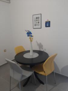 a black table with yellow chairs and a vase with flowers at Apartment Sandra in Rabac