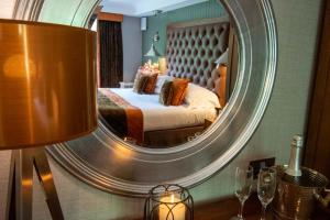 ein Schlafzimmer mit einem Bett mit einem großen Spiegel in der Unterkunft Craigmhor Lodge & Courtyard in Pitlochry