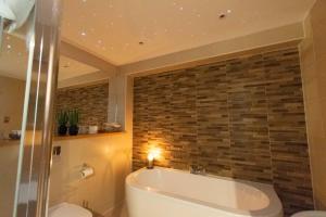 ein Badezimmer mit einer Badewanne und einer Steinmauer in der Unterkunft Craigmhor Lodge & Courtyard in Pitlochry