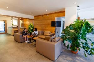 two people sitting on couches in a living room at AUBERGE DES GLIERES in Thorens-Glières