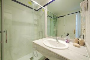 bagno con lavandino e doccia in vetro di Varios apartamentos Romana Playa Elviria a Marbella