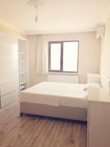 a white bedroom with a bed and a window at Trabzon Meydan in Trabzon