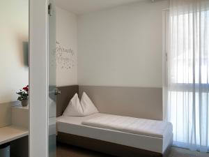 a small bed in a room with a window at Hotel Lokomotive in Linz
