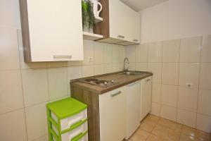 a small kitchen with a sink and a green stool at Apartment Zorica in Supetar
