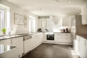 una cocina blanca con armarios y electrodomésticos blancos en Feriebyens Bed & Breakfast, en Rødvig