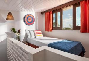 a bedroom with two beds and a couch and windows at Samba do Kite Pousada in Jericoacoara