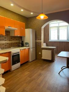 a kitchen with orange cabinets and a white refrigerator at Квартира в новострое in Odesa
