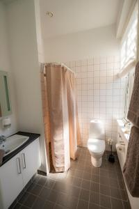a white bathroom with a toilet and a sink at Det Gamle Posthus in Rønne