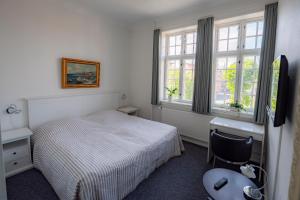 um quarto com uma cama, uma secretária e uma janela em Det Gamle Posthus em Rønne