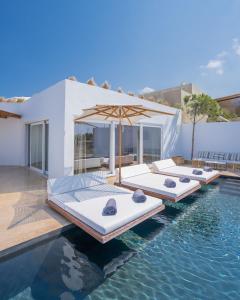 a pool with four beds and an umbrella at Andronis Arcadia Hotel in Oia