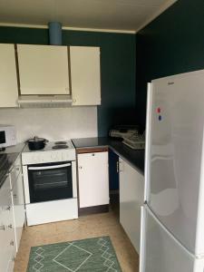 a kitchen with white cabinets and a white refrigerator at Leilighet med balkong og havutsikt på Napp. in Napp