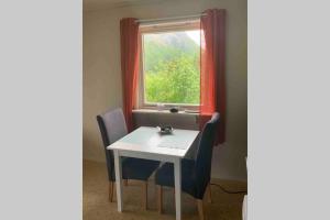una mesa y sillas blancas en una habitación con ventana en Leilighet med balkong og havutsikt på Napp. en Napp