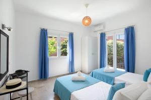 a bedroom with two beds and blue curtains at Irini Apartments and Studios in Agios Gordios