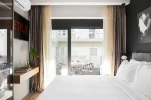 1 dormitorio con cama blanca y balcón en LUX&EASY Athens Downtown Apartments, en Atenas