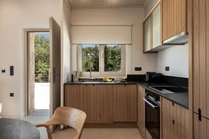 una cucina con armadi in legno, tavolo e finestra di Luxurious new villa Kokomo Gaia w/ Private Pool, 400m to beach a Ligaria