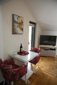 een woonkamer met een tafel en twee stoelen en een televisie bij Apartmani Dijana 2 in Kotor
