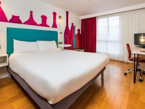 a large white bed in a room with red curtains at ibis Styles Barnsley in Barnsley