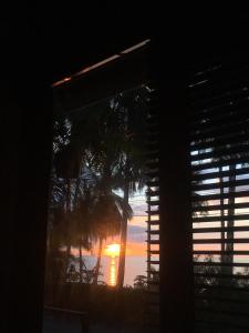 a sunset through a window with a view of the ocean at Jasmine & Tea House in Mae Nam