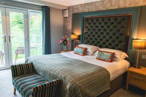 um quarto com uma cama grande e uma cadeira em Craigmhor Lodge & Courtyard em Pitlochry