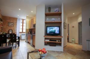 a living room with a television and a dining room at Le Grenier du Chapitre in Sarlat-la-Canéda