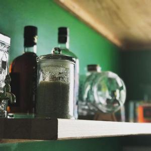 un frasco de líquido verde sentado en un estante con botellas en Studio Carambole by Sweety Stay en Schœlcher