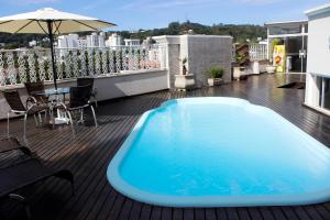 a blue swimming pool on a balcony with an umbrella at Francisco Beltrão Palace Hotel in Francisco Beltrão
