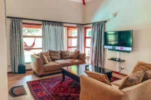 a living room with two couches and a tv at Pecanwood Golf Estate Home - Hartbeespoort in Hartbeespoort