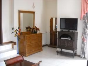 a living room with a television and a wooden dresser at Arouca à Varanda in Arouca