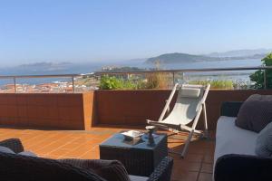 d'une terrasse avec un canapé et une chaise sur un balcon. dans l'établissement Apartamento Familiar con vistas *****, à Baiona