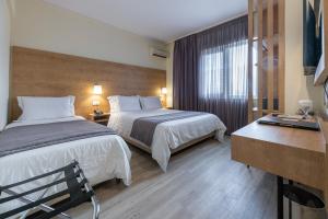 a hotel room with two beds and a window at Polis Grand Hotel in Athens