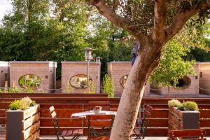 a patio with a table and chairs next to a tree at Zur Post Kümmersbruck Hotel & Tiny Houses in Kümmersbruck