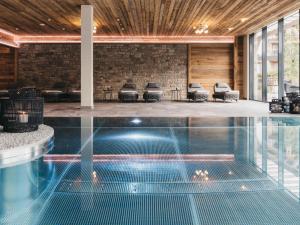 a swimming pool in a building with chairs in the background at VAYA Fieberbrunn in Fieberbrunn