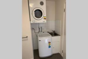 a small kitchen with a sink and a washing machine at Sunny Balcony Over a Calm Private Garden in Melbourne