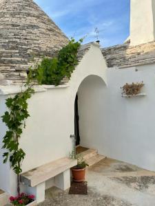 a white building with a bench and plants on it at Trullo Assenzio in Alberobello