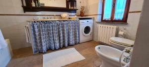 a bathroom with a washing machine and a toilet at Casale dei Puppi una bellissima casa rustica in San Venanzo