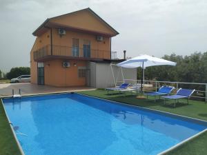 a house with a swimming pool with chairs and an umbrella at Butterfly Room in Scordia