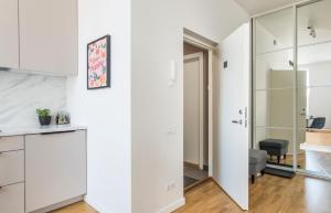 a kitchen with white cabinets and a living room at Cozy Modern Studio in City Centre & QueenSize Bed in Rīga