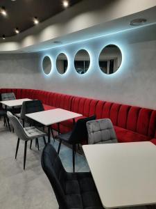 a restaurant with a red couch and tables and chairs at Red Cube Hotel in Kamianets-Podilskyi