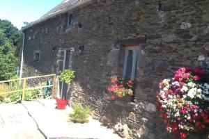 una casa de piedra con flores delante en Les Ecuries is a modern renovated barn, en Laniscat