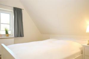 a white bed in a room with a window at An der Steilküste Wohnung 03 in Boltenhagen