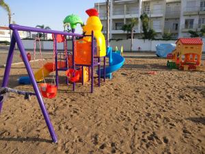 einen Spielplatz im Sand vor einem Gebäude in der Unterkunft Casabay Appart Vue Sur Piscine in Sidi Rahal