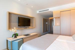a bedroom with a bed and a tv on the wall at Hipotels Barrosa Park in Chiclana de la Frontera