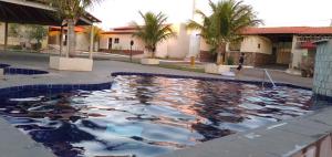 una piscina de agua con una persona caminando delante de un edificio en Casa Condomínio Ipê, Mansões das Águas Quente, en Caldas Novas