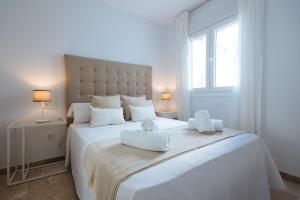 um quarto branco com uma grande cama branca e 2 toalhas em Triana Home - Free Parking em Sevilha