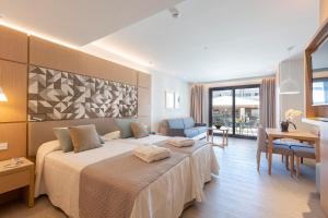 a hotel room with a bed and a dining room at Hipotels Barrosa Park in Chiclana de la Frontera