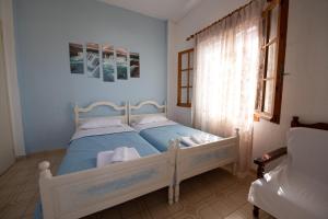 a bedroom with a bed with blue sheets and a window at Eleni Studios Neo Klima Skopelos in Skopelos Town