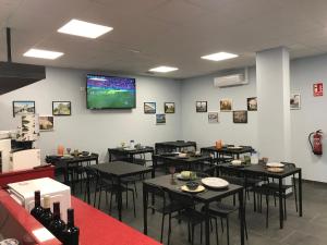 a dining room with tables and a tv on the wall at Hostel & Rooms O Albergue da Meiga in Padrón