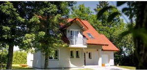 a small white house with an orange roof at Grabina Mazury in Stare Juchy